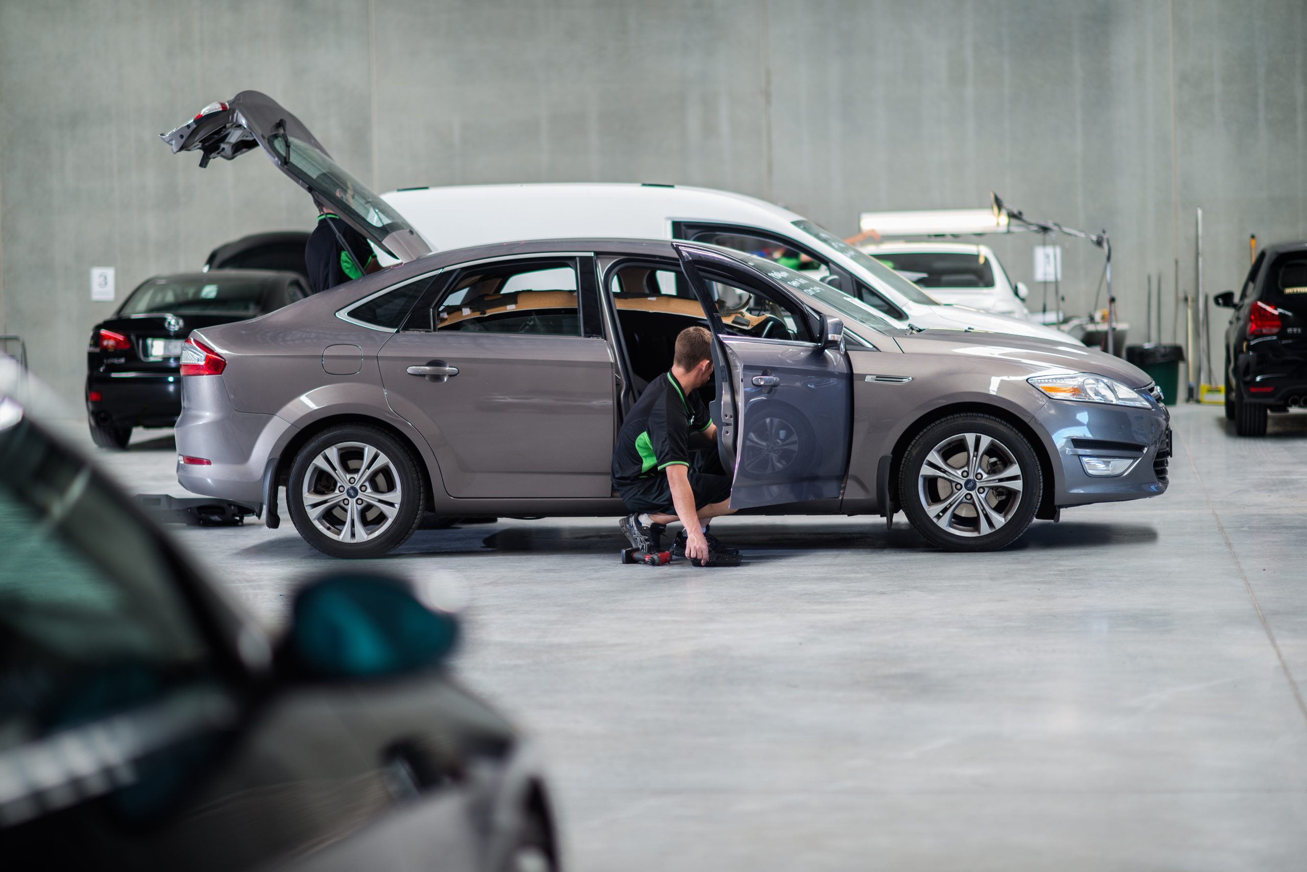 UHR technician working on a silver car inside a repair facility